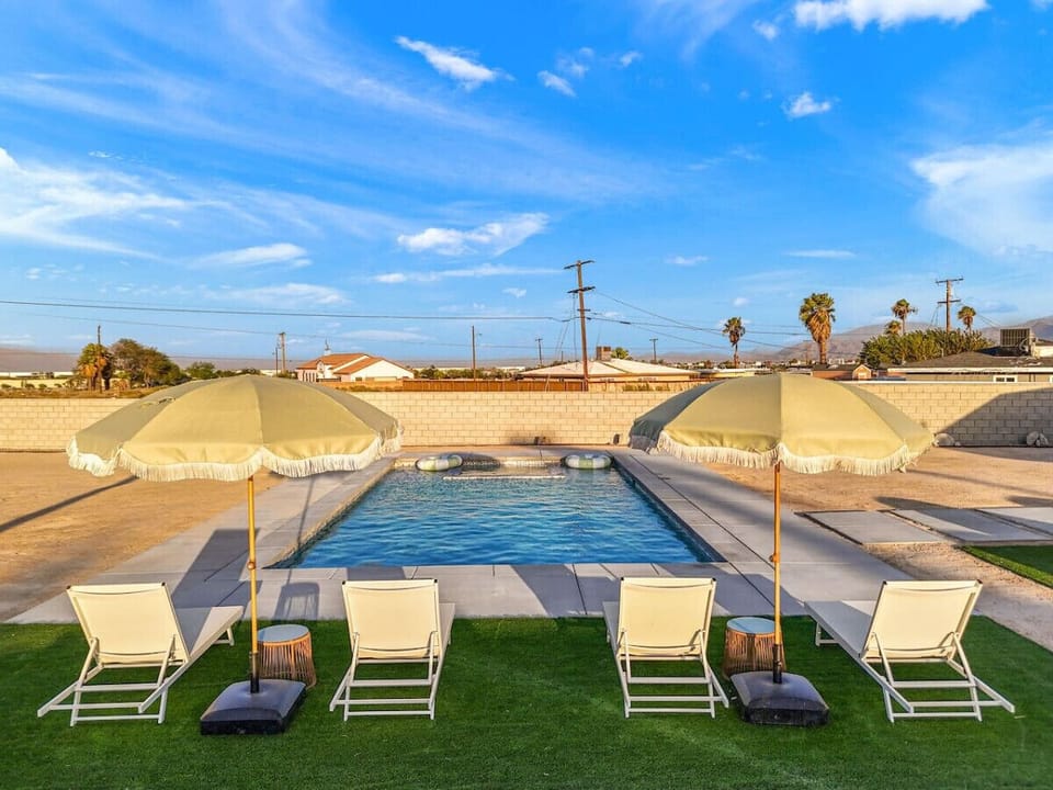 Sunlit backyard pool w/ loungers and mountain views, perfect for cooling off after a day in the desert.