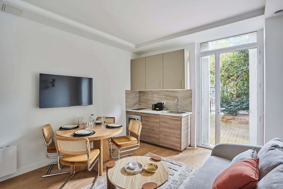 Salon avec canapé lit, TV, et espace repas pour 4 personnes