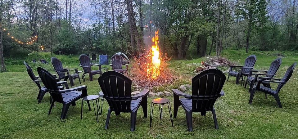 Adirondack chairs surrounding the large firepit in the backyard for all guests