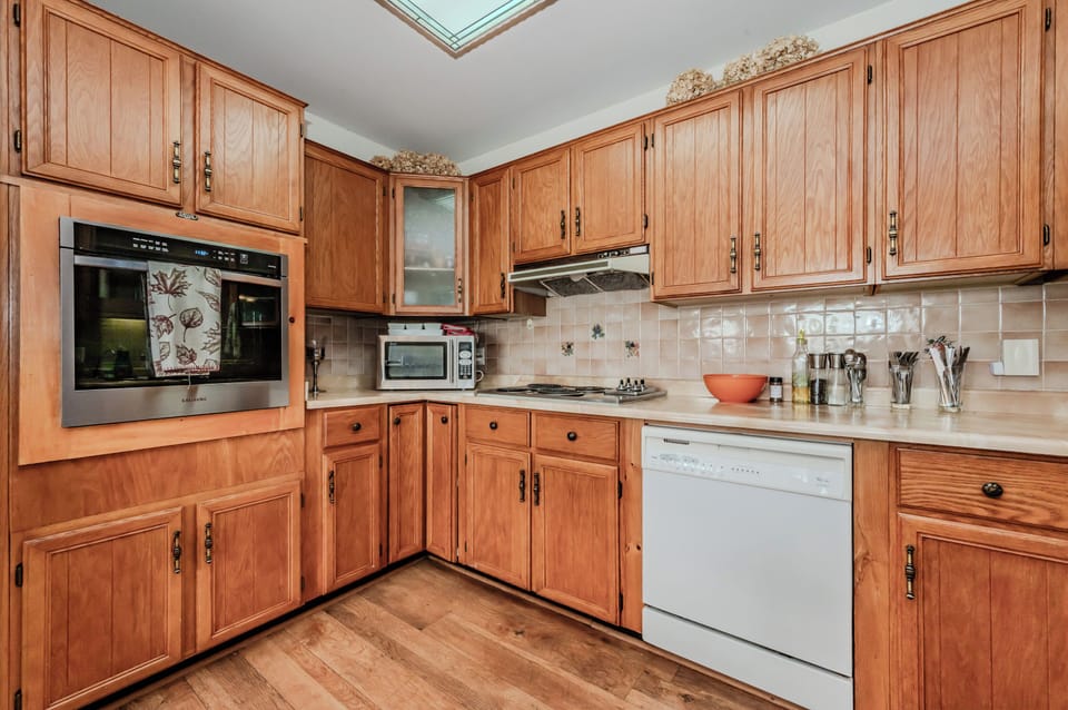 The kitchen is both functional and inviting, equipped with stainless steel appliances, including a modern stove and dishwasher. 