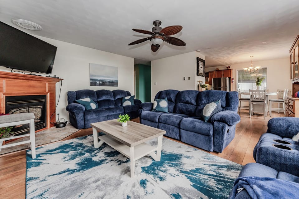 Unwind in the cozy living room, complete with plush blue sofas and a fireplace—perfect for family gatherings or a quiet evening in.