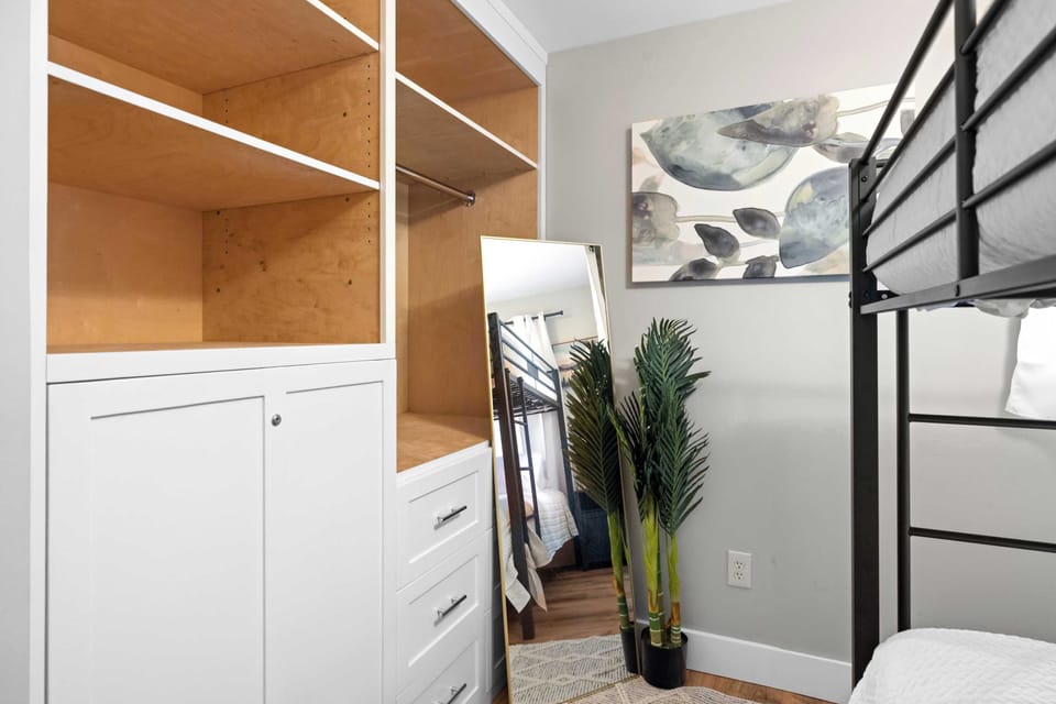 Modern bedroom corner with a metal bunk bed, built-in storage, and a full-length mirror.