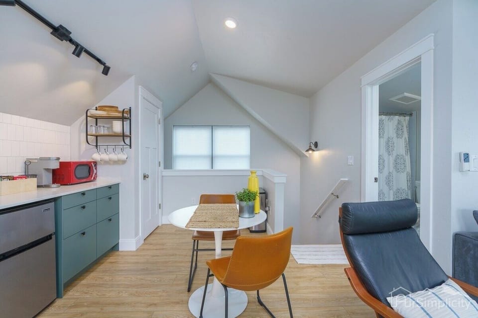- Modern open plan layout with dining for two and a view into the loft style landing
- Clean architectural lines and vaulted ceiling elevate this airy space
- Pops of yellow and greenery bring a fresh feel to the minimalist design