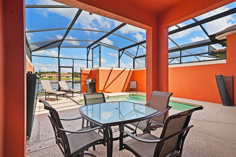 - Inviting outdoor patio with a covered dining area, perfect for enjoying meals by the pool - Private screened pool, lounge chairs offer a relaxing retreat under the sun - Bright orange walls and a BBQ grill add warmth and functionality to the space