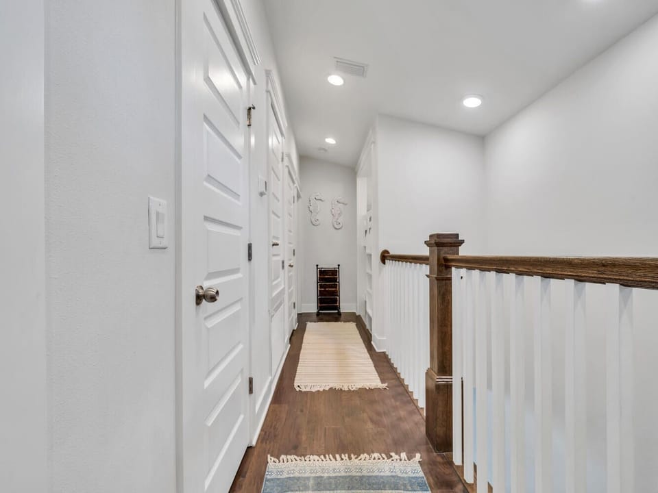Step into your private upstairs hallway featuring warm hardwood floors, built-in storage, and bright modern lighting.