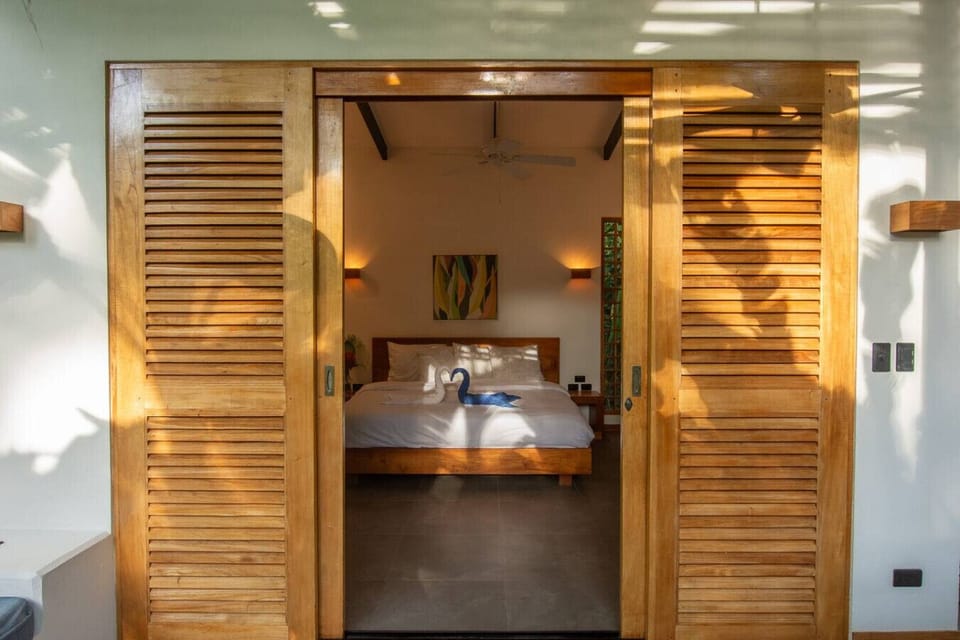 Bedroom entrance with sliding wooden doors and king bed at Tres Lodge Tucan, Playa Chiquita