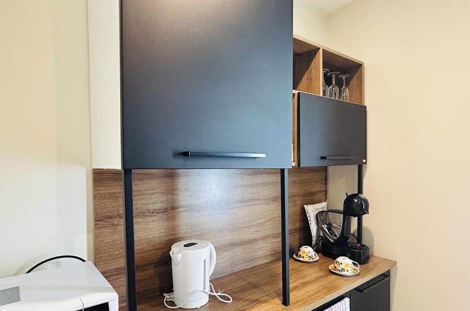 A tidy and compact kitchenette area featuring black cabinets, shelving