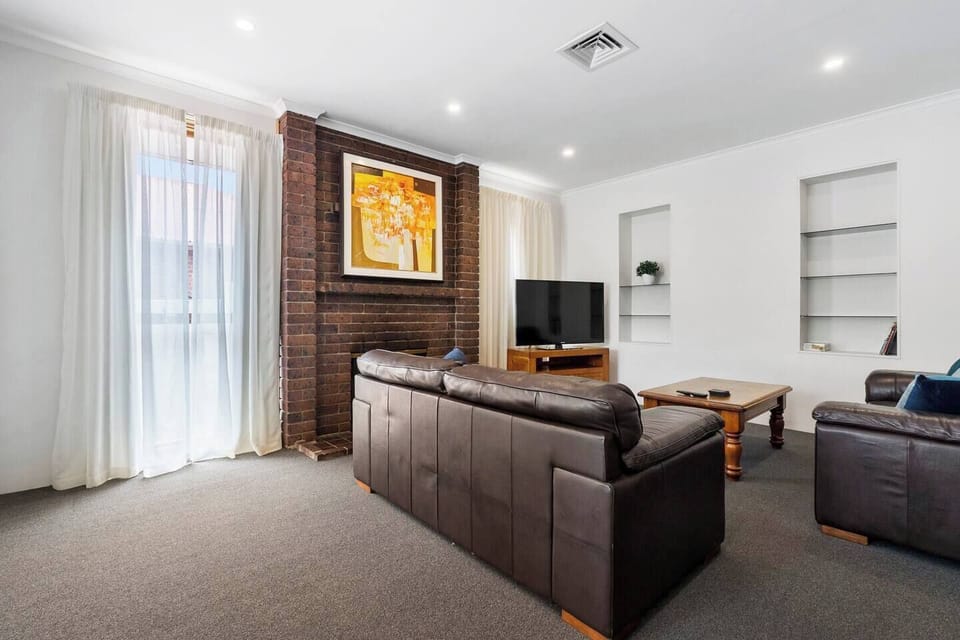 The living area is set with two leather lounges fronting a central TV.