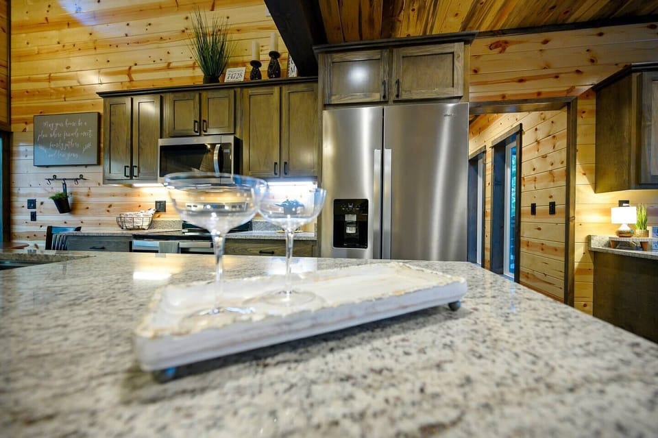 Elegant details on the granite kitchen island create the perfect spot to gather and enjoy a drink. The surrounding modern appliances and natural wood accents blend seamlessly, adding to the cabin’s warm and inviting atmosphere.