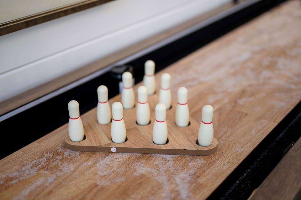 Mini tabletop bowling game on rustic shuffleboard, perfect for fun indoor entertainment in vacation cabin.