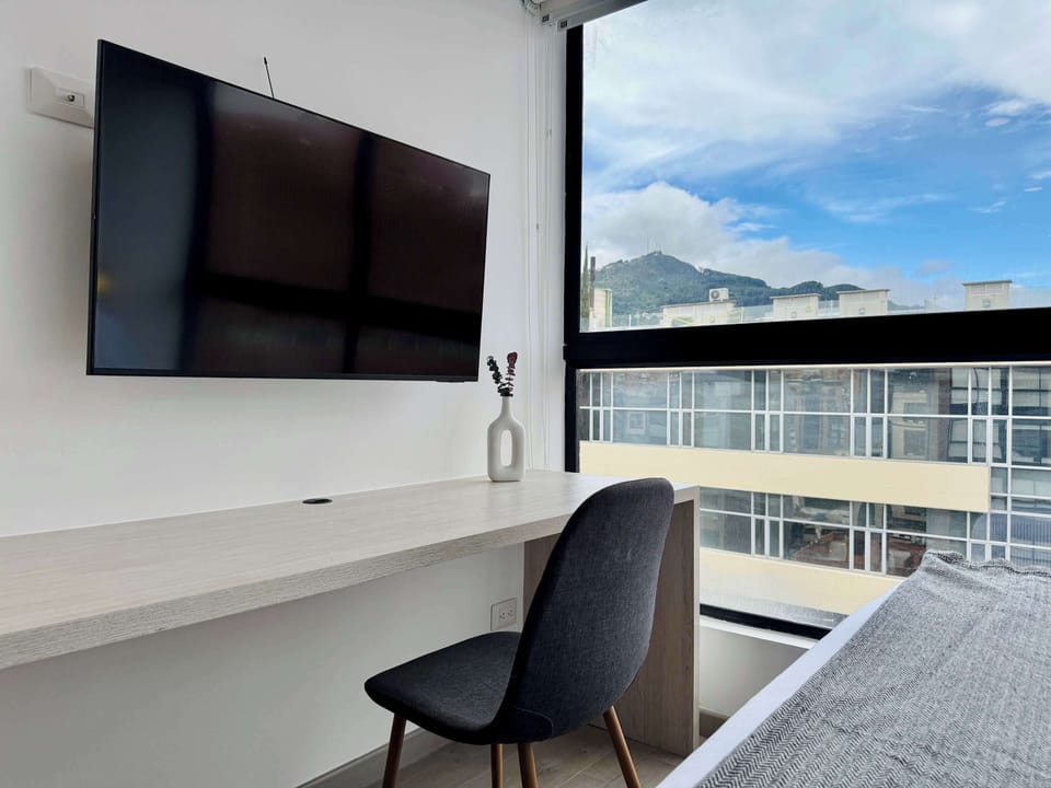 Mounted TV and a desk near a balcony with views.