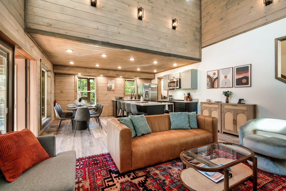The living room has beautiful Cathedral ceilings & large windows w/ wooden views