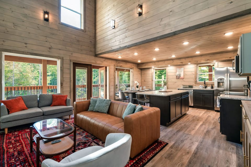 The living room has beautiful Cathedral ceilings & large windows w/ wooden views