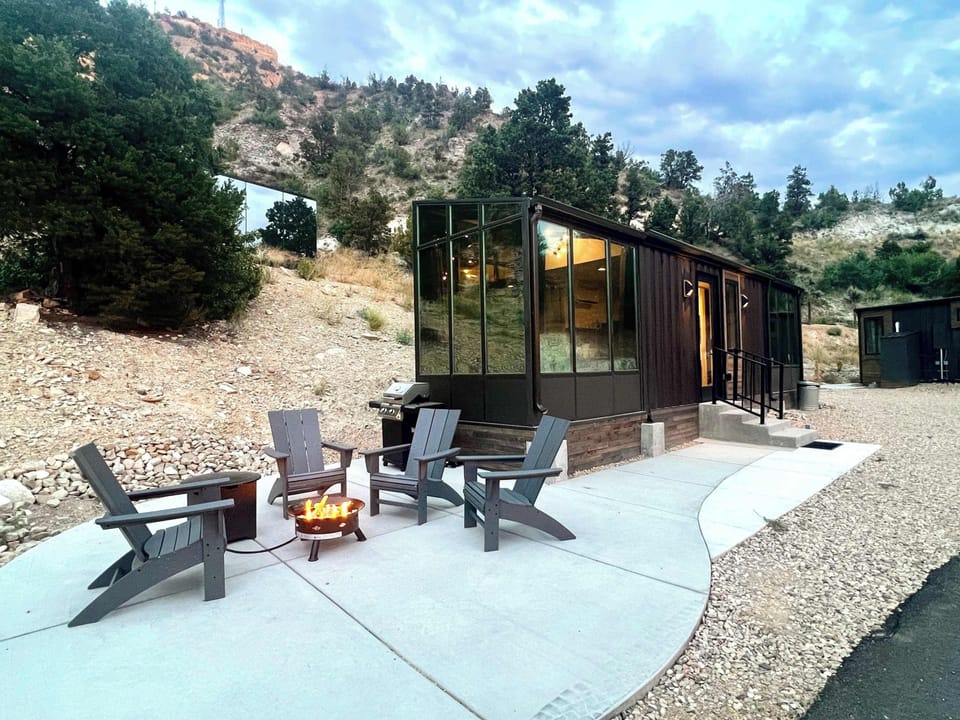 Exterior view of Red Hollow, a modern container cabin at East Zion Resort with large windows, mountain views, and peaceful Southern Utah scenery.