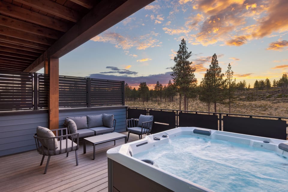 Evening sunset view of the private balcony featuring a hot tub and lounge seating.