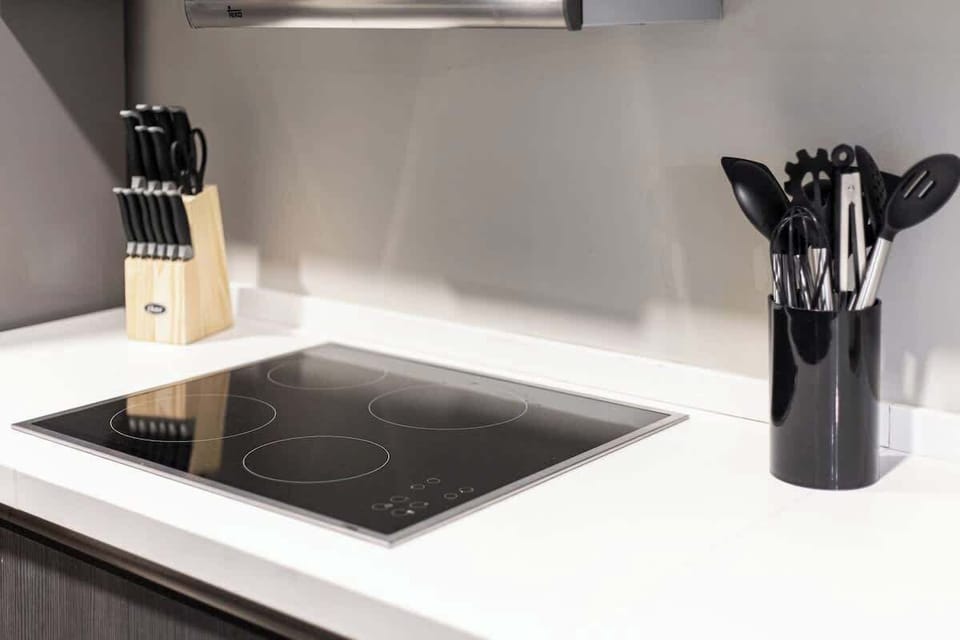 Modern kitchen detail with an electric glass cooktop and cooking utensils ready for meal prep.