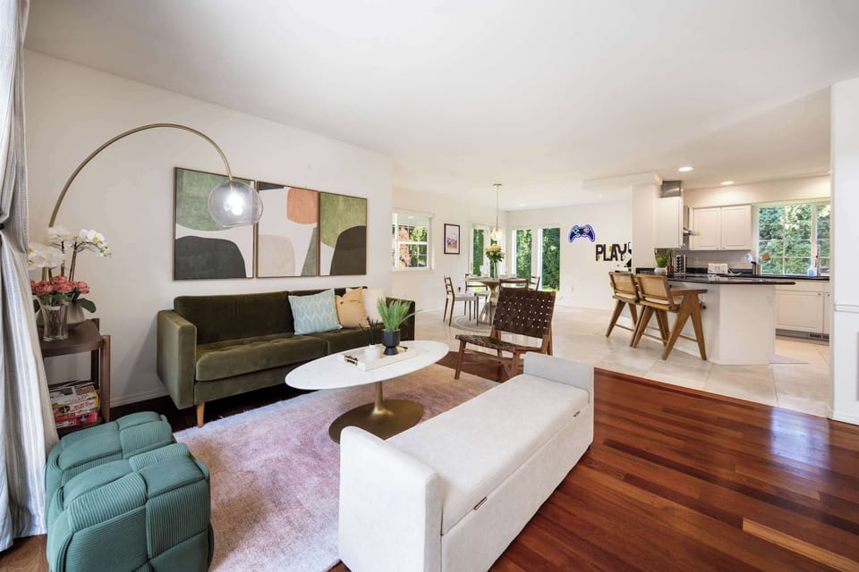 A living room with a modern, elegant design featuring a chic green sofa and warm wood accents. The perfect spot to relax with a book or catch up on your favorite shows.