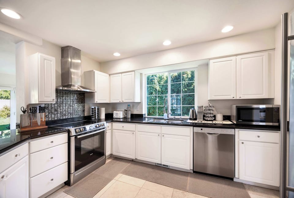 A bright, modern kitchen with sleek stainless steel appliances, white cabinetry, and plenty of natural light. A perfect space to cook up your favorite meals.
