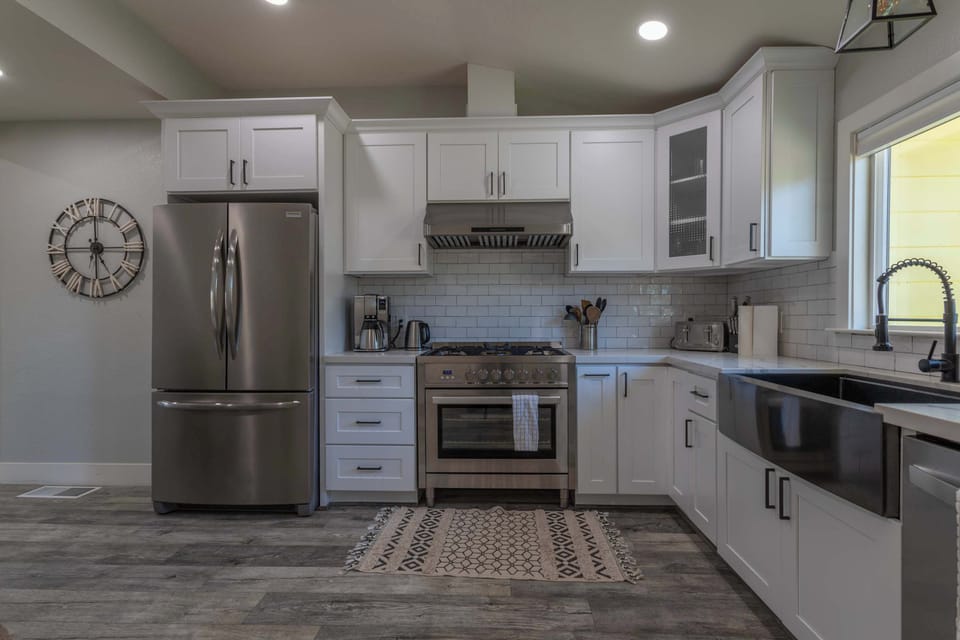 Cook in style in this pristine farmhouse kitchen, complete with stainless steel appliances, a gas stove, and a deep sink—all framed by bright white cupboards and ample counter space.