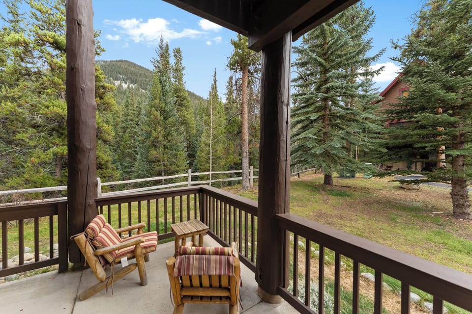Unwind on your private balcony with stunning mountain views, where comfortable seating invites peaceful moments among towering pines.