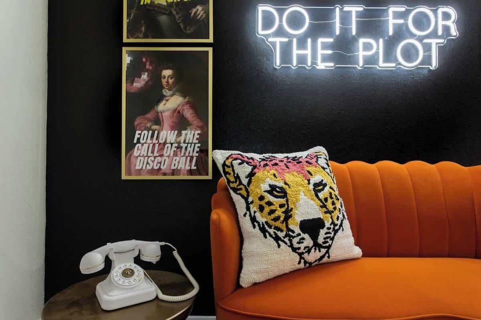 Snap a pic in this stylish corner featuring a cozy couch, unique artwork, and a vintage telephone paired with a sleek light stand. ️