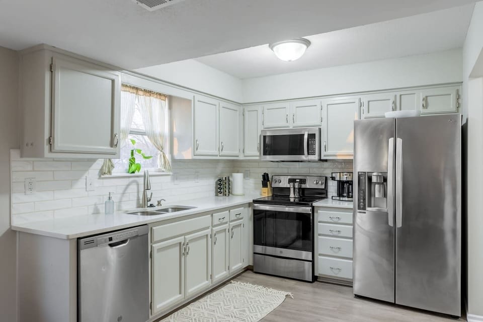 A modern kitchen featuring stainless steel appliances, quartz countertops, and a stylish tile backsplash. The sleek design and high-end finishes create a perfect blend of functionality and elegance.