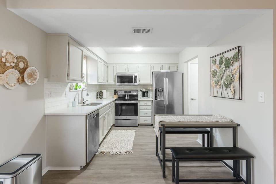 A modern kitchen featuring stainless steel appliances, quartz countertops, and a stylish tile backsplash. The sleek design and high-end finishes create a perfect blend of functionality and elegance.