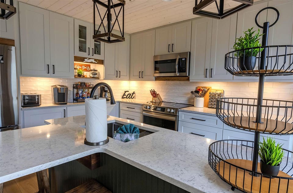 The gourmet kitchen, with beautiful quartz countertops, features modern cabinets with under cabinet lights, and an oven with an integrated air fryer.