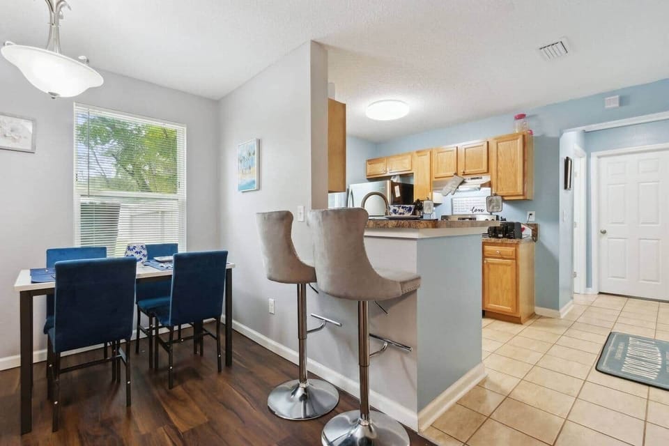 Enjoy a casual breakfast bar at the kitchen counter with the convenient grey high stool chair or gather for a more formal meal at the blue dining table with seating for four in the sunlit dining area.