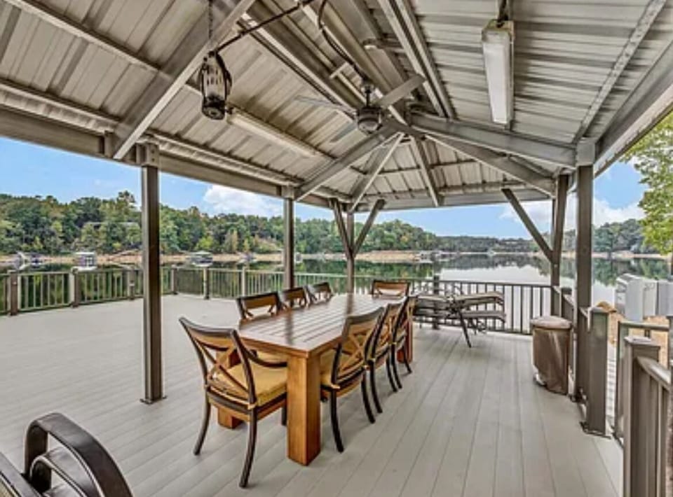 Covered upper deck on dock with dining table set and 6 lounge chairs.