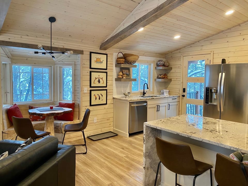A generous living room area with beautiful windows, stone fireplace and cozy breakfast nook leads into the full kitchen
