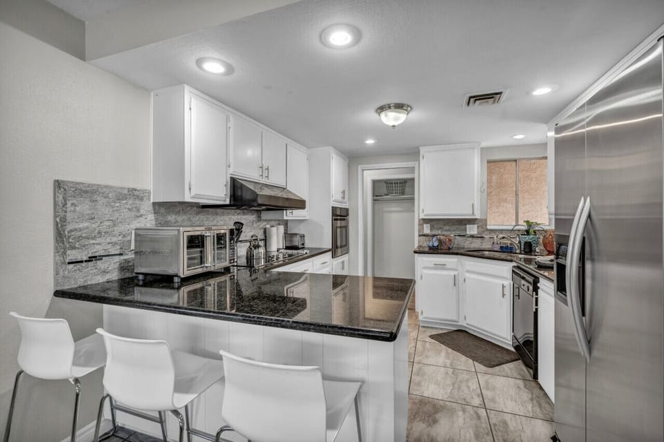 This modern kitchen boasts sleek granite countertops, stainless steel appliances, and a spacious island with seating—perfect for cooking, dining, and gathering.