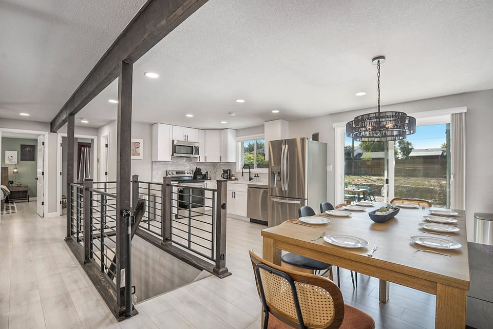 Bright and stylish open floor plan connecting the living room, dining area, and kitchen, with a chic staircase leading to the lower level.