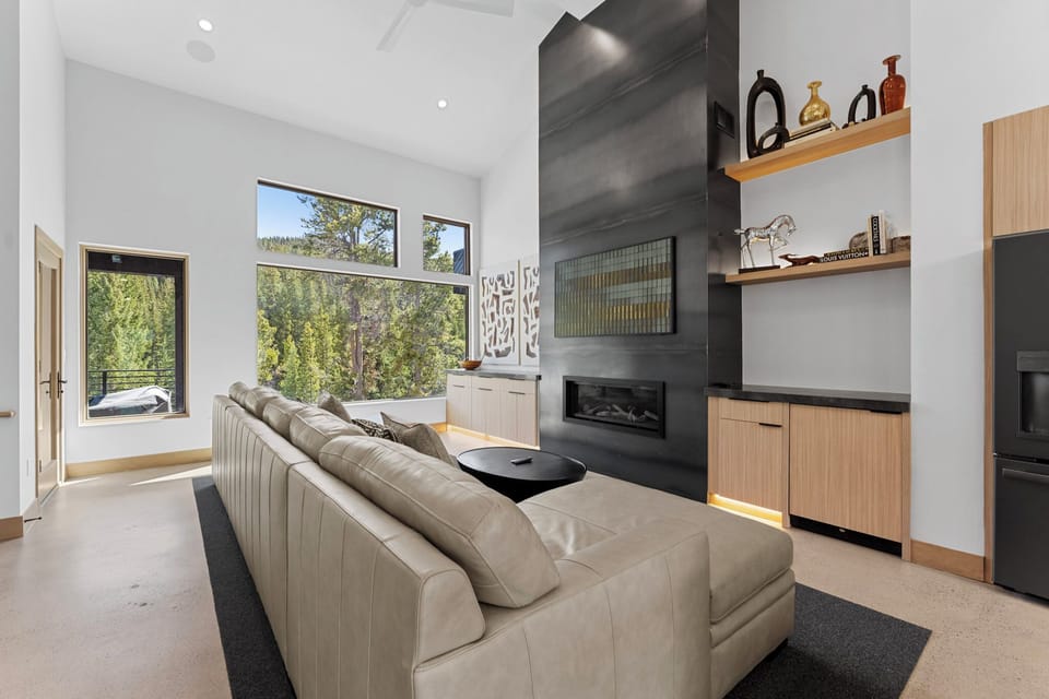 Open-concept living area featuring a mounted TV over a gas fireplace, balcony access, and dry bar with wine fridge.