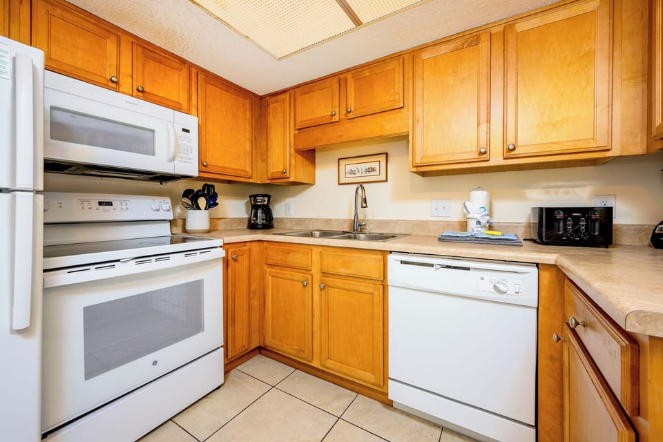 Kitchen featuring white appliances, warm wood cabinetry, and a convenient coffee maker for your stay