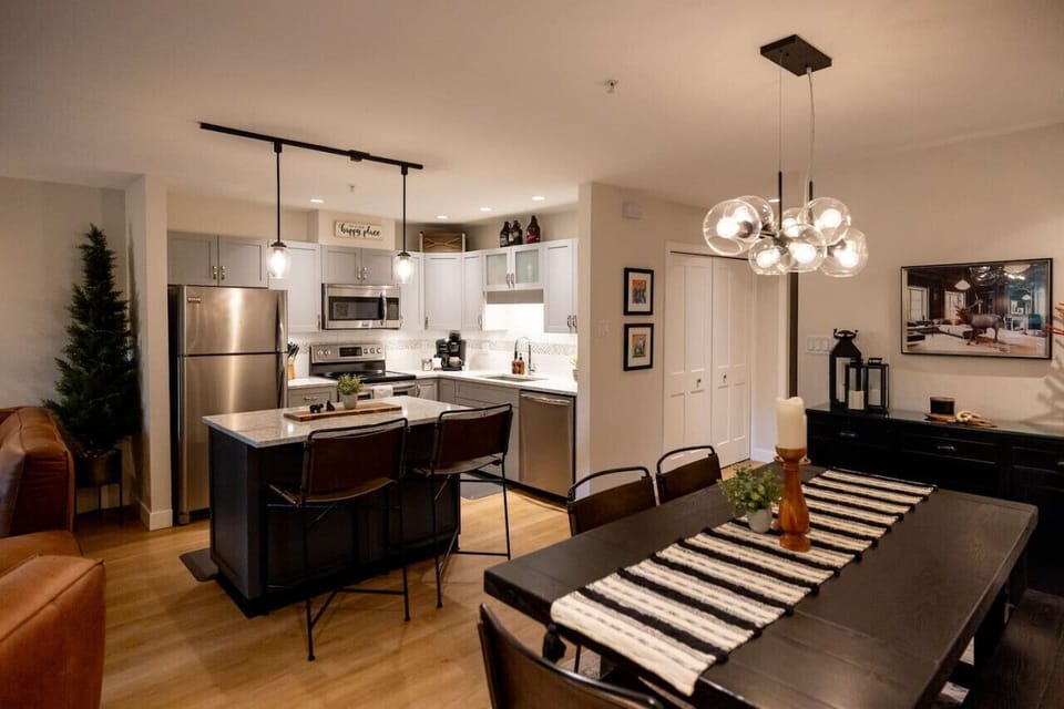 Pendant lights illuminate the space, with a sneak peek of the dining table, creating a warm and inviting atmosphere that enhances the kitchen’s aesthetic. An open layout is great for the family