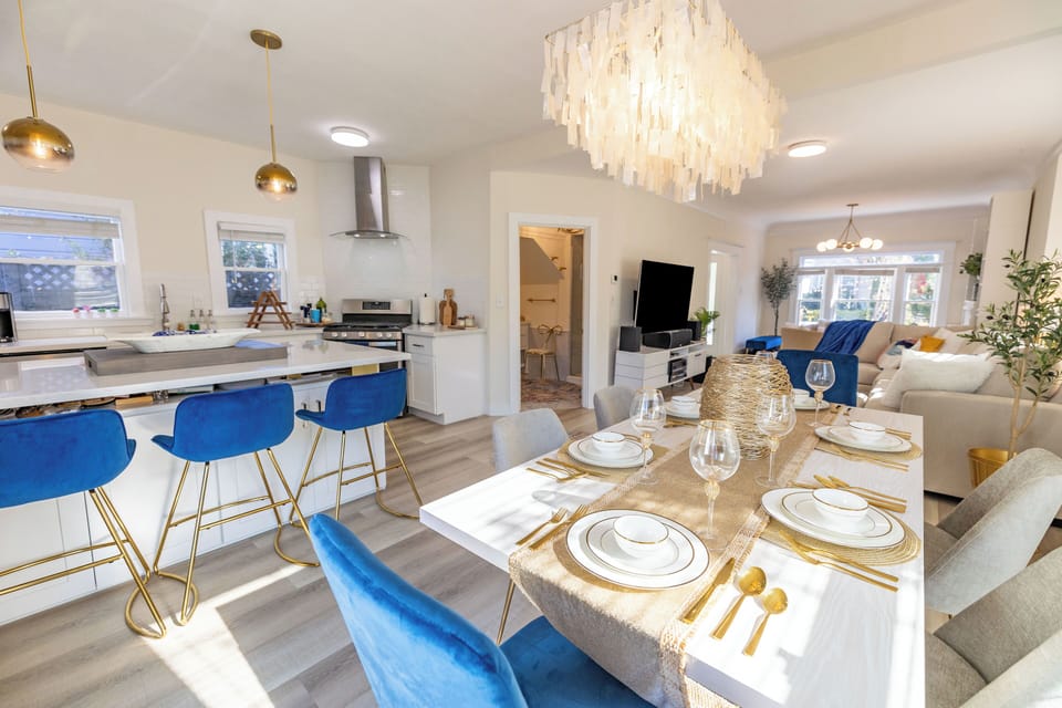An elegant 6-seater dining area with a white table, and golden utensils.
