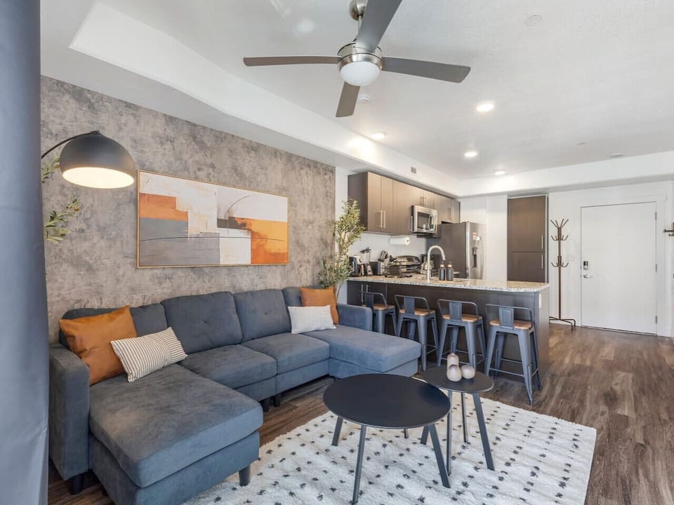 Open-concept living area with a stylish sectional, modern kitchen, and plenty of space to relax or entertain 🛋️✨🍷