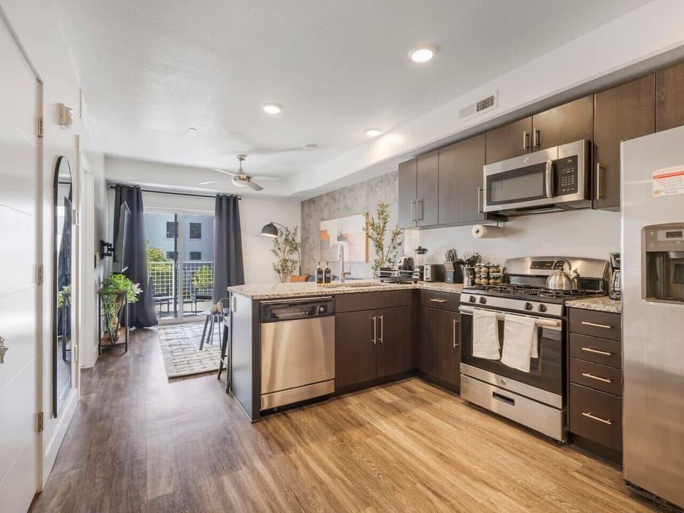Bright open kitchen with stainless steel appliances, granite counters, and balcony access for fresh air and natural light ✨🌿🍴