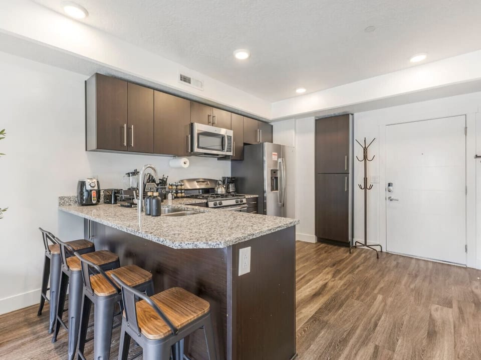 Modern kitchen with bar seating, stainless steel appliances, and all essentials 🍴☕✨—perfect for meals or morning coffee!