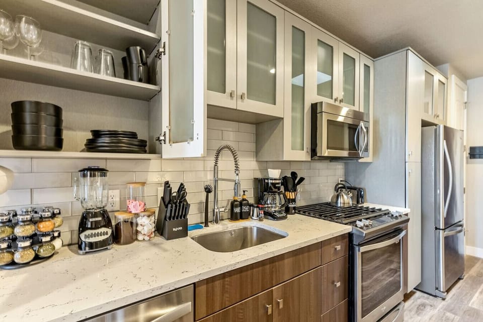 Well-equipped kitchen w/ granite counters, open shelving & stainless appliances
