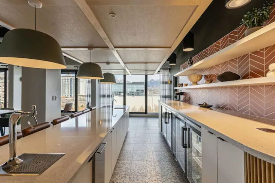 Sleek shared kitchen w/ long counters, bar seating & modern finishes