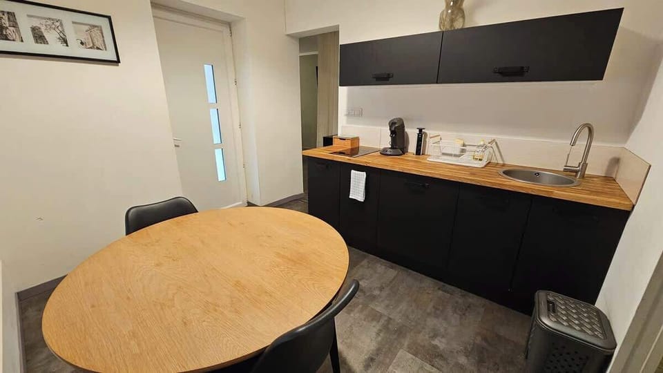 Cuisine équipée avec bouilloire, machine à café, plaques de cuisson, micro-ondes et petit réfrigérateur.
Table à manger pour deux personnes.