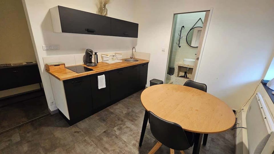 Cuisine équipée avec bouilloire, machine à café, plaques de cuisson, micro-ondes et petit réfrigérateur.
Table à manger pour deux personnes.