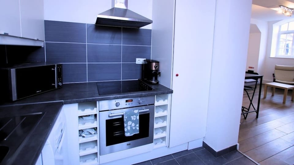 Cuisine équipée avec réfrigérateur avec freezer, lave-vaisselle, micro-ondes, machine à café, bouilloire, plaques de cuisson et four.