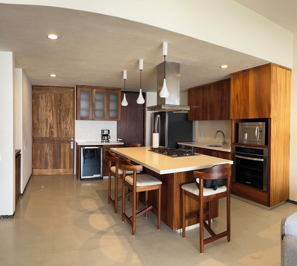 A contemporary kitchen featuring wood finishes, modern appliances, and an island with seating for entertaining.