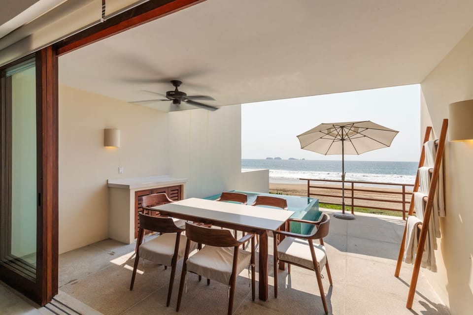 Enjoy al fresco dining with breathtaking ocean views, a shaded pergola, and a modern outdoor kitchen setup.