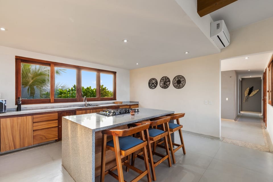 A fully equipped kitchen and dining area featuring sleek wood finishes and ocean-view seating for the perfect vacation meals.