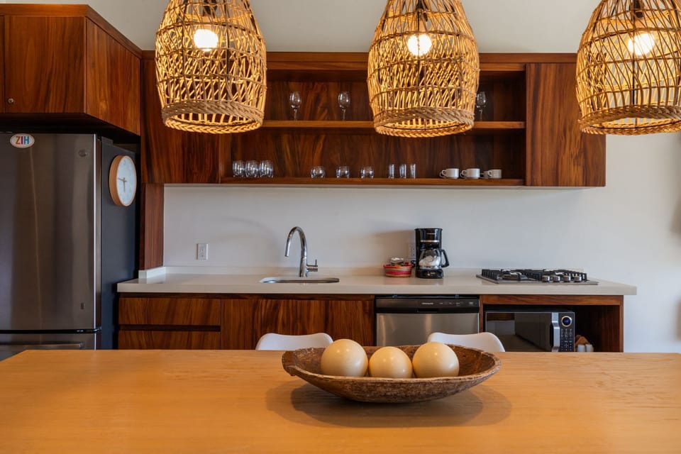 A gourmet kitchen featuring handcrafted wooden cabinetry, woven pendant lighting, and state-of-the-art appliances for a premium cooking experience.
