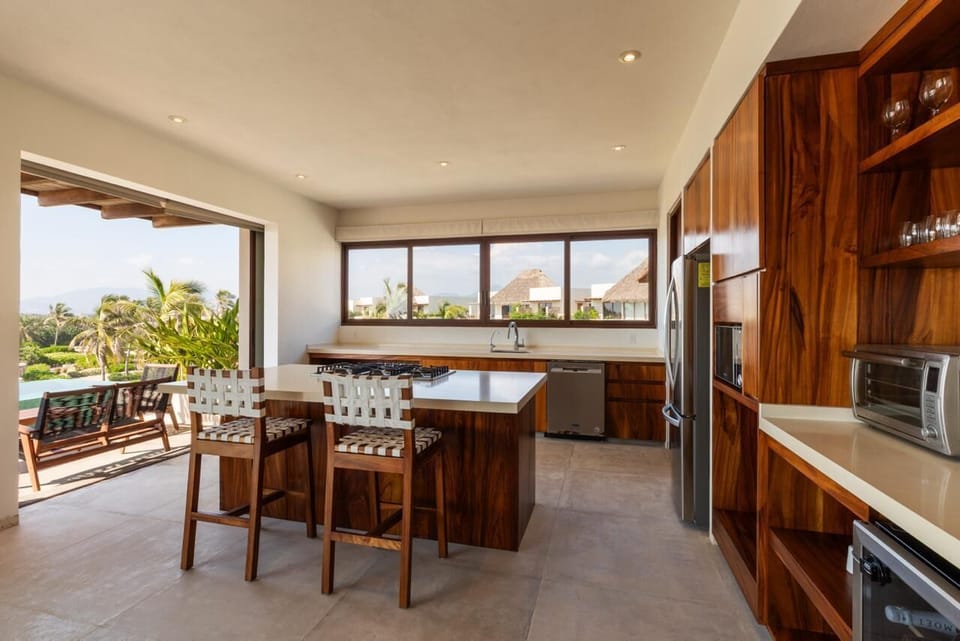 This fully equipped kitchen blends functionality with style, featuring high-end appliances and a stunning coastal backdrop.
